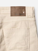 Close-up of the back pocket and waistband of BGpaulo Pavia 1 V2 Chino - Ecru by Blue de Gênes, showing a brown leather brand patch and red-and-white crest, crafted from comfortable cotton stretch fabric.