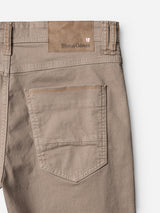 Close-up of the BGpaulo Pavia 1 V2 Chino - Fungi by Blue de Gênes, showing beige cotton stretch fabric, a single back pocket, and a brown leather patch with the Blue de Gênes name and red-white shield logo above the pocket.