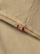 Close-up of tan cotton stretch fabric from Blue de Gênes BGpaulo Pavia 1 V2 Chino - Khaki, featuring two intersecting seams with orange stitching and red thread reinforcement, highlighting the garment’s durable construction.