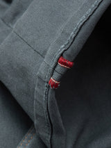 Close-up of Blue de Gênes Paulo Pavia 1 V2 Chino in Charcoal: dark blue cotton stretch fabric denim with visible selvedge edge plus red and white stitching, evoking the detailed quality of vintage military pants.