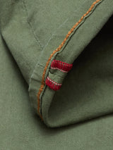 Close-up of green cotton stretch fabric with orange stitching and two small red and white stitched bars at the edge, featured on the Paulo Pavia 1 V2 Chino - Army by Blue de Gênes.