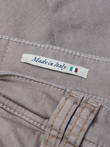 A close-up of the Blue de Gênes Paulo Pavia 1 V2 Chino - Fungi label sewn onto light brown fabric, marked Made in Italy with a small Italian flag and orange stitching on these vintage-inspired military pants.