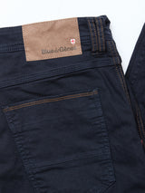 Close-up of the back pocket and waistband of the Paulo Pavia 1 V2 Chino in Midnight Blue by Blue de Gênes, made from cotton stretch fabric with brown stitching, a tan Blue de Gênes leather patch, and a red and white shield logo.
