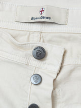 Close-up of BGpaulo Pavia 1 V2 Chino - Ecru pants by Blue de Gênes, featuring cream cotton stretch denim, metal buttons, signature label with shield logo, and vintage military-inspired waistband and stitching.