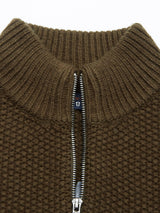 Close-up of the Aimone Knit Cardigan in brown lambswool by Blue de GĂȘnes, featuring a textured knit and half-zip high ribbed collar, partially open to reveal a small fabric tab beneath.