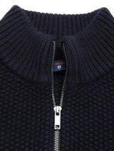 Close-up of the Aimone Knit Cardigan in dark navy by Blue de Gênes, featuring a ribbed high collar and chunky pattern. The silver zipper is partially unzipped, revealing a label inside.