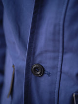 Close-up of the BGcanopy Jacket - Navy Peony by Blue de Gênes, featuring a black button, zippered pocket, visible stitching, and textured fabric.