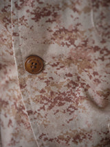 A close-up of the BGkendrick Print Jacket - Multi Pattern by Blue de Gênes showcases its beige and brown digital camo workwear fabric and rugged brown button, highlighting the detailed craftsmanship of this classic piece.