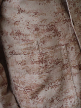 Close-up of the BGkendrick Print Jacket by Blue de Gênes shows a beige and brown desert camo pattern on durable cotton twill, featuring a pocket and part of a button-down shirt—classic details for this multi-pattern worker jacket.