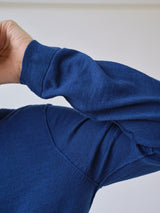 A close-up shows a person wearing the Blue de Gênes BGmonty Knit in Navy Peony, with their arm bent at the elbow and part of the upper body visible against a light, neutral background.