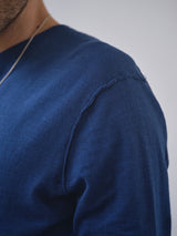 Close-up of a person wearing the BGmonty Knit - Navy Peony by Blue de Gênes, showing visible shoulder seam stitching. Part of the neck, shoulder, chest, and a thin silver necklace are visible against a blurred neutral background.