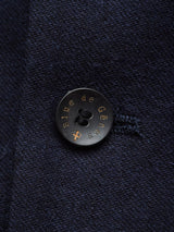 Close-up of a black button on dark blue fabric, embossed with Blue de Gênes. The Canna Carbonio Gillet in Dark Navy features sophisticated Buffalo horn buttons and is made from Italian brushed cotton.