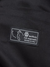 Close-up of a black fabric label with white text reading Canna Carbonio Gillet by Blue de Gênes, featuring its Italian craftsmanship. Crafted from exquisite dark navy brushed cotton, it includes WOVEN IN ITALY and a line drawing of Italy.