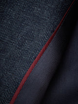 A close-up of dark denim fabric folded over with a red selvedge edge displays its finely woven texture, echoing the meticulous craftsmanship of the Blue de Gênes Casella Wasabi Blazer - Denim Blue, highlighting a contrast between smooth and textured surfaces.
