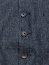 A close-up of the Casella Wasabi Blazer by Blue de Gênes in denim blue reveals its intricate weave pattern. It features three black buffalo horn buttons with gold lettering on the right side, each securely fastened with matching thread.