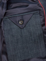 Close-up of the Casella Wasabi Blazer by Blue de Gênes, showcasing a denim-style pocket with a black buffalo horn button. The pocket has a triangular flap, and the lining is finished with thin red piping.