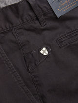 Close-up of the pocket area of Franco Genes Chino - Charcoal by Blue de Gênes, featuring a shield-shaped cross emblem. A garment-dyed tag with logo/text is visible, along with prominent stitching and a button detail similar to classic Saia twill chinos.
