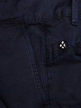 Close-up of Blue de Gênes Franco Genes Chino in navy. The garment-dyed pants feature a side pocket with a button flap and white cross button accent. Made from textured Saia twill, these stylish chinos have character.