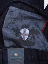 Close-up of Franco Genes Chino - Navy jeans by Blue de Gênes, crafted from dark blue Saia twill, featuring an inner lining with a printed crest of a shield and two griffins. A small tag reads Progetto Heritage Blue de Gênes with a signature.