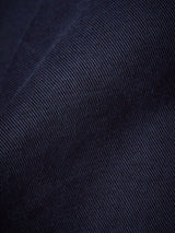 Close-up of the Franco Genes Chino in Navy by Blue de Gênes, showcasing its dark blue fabric with a visible diagonal ribbed texture. The folds highlight subtle shading variations, emphasizing the garment-dyed woven pattern and adding depth to the image.