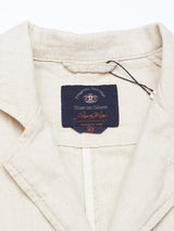 Close-up of the Gabbiano Winnot Blazer collar in light beige, crafted from cotton linen by Blue de Gênes. The navy label with decorative white stitching has a black string attached, giving it a relaxed blazer style.