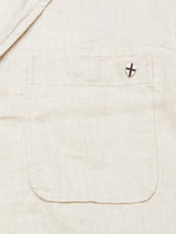A close-up of the Gabbiano Winnot Blazer - Natural by Blue de Gênes reveals beige cotton linen fabric with a front pocket, featuring a cross design pin in the upper right corner. The blazers subtle herringbone pattern enhances its sophisticated texture.
