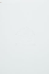 Embossed text on a light surface reads Progetto Heritage Blue de Gênes with an intricate emblem, giving it a vintage look akin to the charming complexities of the BDG Leather Journal - Brown by Blue de Gênes, crafted from premium bull leather.