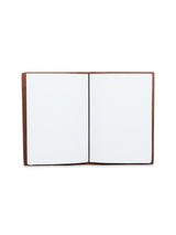 A BDG Leather Journal by Blue de Gênes in brown leather is open to reveal two blank A5 white pages against a plain white backdrop, its premium bull leather cover offering a vintage appeal.