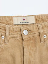 Close-up of BGgiacomo Color Jeans - Tanin by Blue de Gênes in rigid denim, showing the waistband, belt loops, metallic button with shield emblem, and fabric label featuring Blue de Gênes with a red and white shield logo.