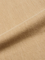 Close-up of Tanin BGgiacomo Color Jeans by Blue de Gênes: light tan fabric with a visible diagonal weave, prominent fold, and a soft, slightly fuzzy texture reminiscent of rigid denim.