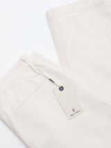 A pair of BGpalco Twill Pants - Chalk by Blue de Gênes, featuring an off-white men's relaxed fit in cotton twill with a back pocket and a white tag with the text Blue de Gênes.