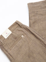 A pair of BGpalco Lin Pants in Grey Mel by Blue de Gênes, neatly folded to display the back pocket with a white label and a cream brand tag peeking from the waistband—a refined summer essential.
