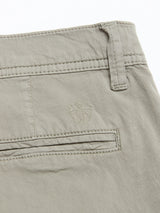 Close-up of the back pocket of Blue de Gênes BGmenzino Vecchio Shorts in Shadow Green, featuring a shield stitched above the pocket and a waistband belt loop for a classic casual look.