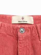 Close-up of the waistband on BGfloyd Cord Shorts - Coral by Blue de Gênes, showing a metal button and a fabric label with a shield logo and the brand name.