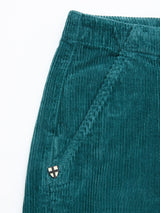 Close-up of Blue de Gênes BGfloyd Cord Shorts in Green Harvest—a garment-dyed teal green cotton corduroy short featuring an elastic waistband, diagonal side pocket, and a small shield patch near the pocket.