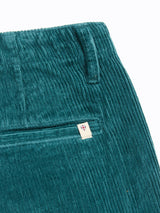 Close-up of Blue de Gênes BGfloyd Cord Shorts - Green Harvest, featuring a waistband, vertical side pocket, and back pocket with a small white tag displaying a red and blue shield emblem.