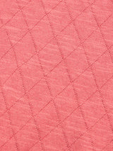 Close-up of the BGwally Diamond Polo - Coral by Blue de Gênes, showcasing its pink diamond-quilted fabric with intersecting stitched lines that create a textured, knit-inspired pattern.
