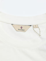 Close-up of the BGoscar T-Shirt - Snow Fall by Blue de Gênes: white cotton, regular fit, beige label with a red and white crest and "Blue de Gênes" text at neck, plus an L size tag attached with a string.