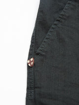 A close-up of the pocket on a Blue de GĂȘnes jacket reveals a small red and beige shield-shaped pin near the top corner. The fabric, expertly crafted in Italy, adds an elegant touch to this piece.