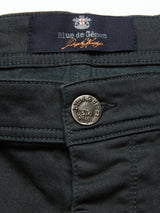 Close-up of a pair of jet black Paulo Pavia 1 Chino pants by Blue de GĂȘnes, featuring an inner waistband label. Made in Italy from cotton stretch fabric, they include a silver button engraved with Blue de GĂȘnes and an emblem above the zipper.