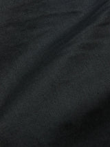 Close-up of Paulo Pavia 1 Chino - Jet Black by Blue de GĂȘnes, crafted from dark cotton stretch fabric in Italy, showing fine threads and a subtle diagonal fold creating shadows and shades of black and gray.