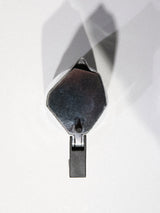 A grey BDG Coffee Maker by Blue de Gênes rests on a white surface, its sleek form casting a clear shadow behind it. The coffee maker stands upright, handles pointing down.