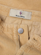 Close-up of BGfloyd Cord Shorts in Pale Khaki by Blue de Gênes, showing a partially opened zipper, a metal button engraved with the brand name, and a fabric label featuring the logo and shield.