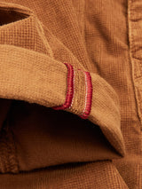 Close-up of Paulo Tucan Chino - Biscotto by Blue de Gênes, showcasing comfort stretch corduroy fabric with a folded edge and red stitched accent. Made in Italy, the texture and stitching details stand out vividly.