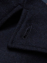 Close-up of the Peacoat - Dark Navy by Blue de Gênes, showcasing a buttonhole detail on the lapel. The Melton wools texture and stitching are clearly visible, with branded buffalo horn buttons that highlight the garments craftsmanship.