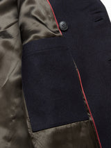 A close-up of the interior of the Peacoat - Dark Navy by Blue de Gênes shows a dark green satin-like lining, a dark Melton wool pocket with red piping, and a branded buffalo horn button near the top right.