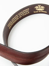 Close-up of the Pento Belt - Brown by Blue de Gênes, crafted from full-grain bull leather with a herringbone pattern. Gold embossing reads: Full Grain Leather, Vegetable Tanned, Handmade in Italy. Logo also embossed on the inner side.