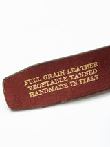 Close-up of a leather item with gold text: FULL GRAIN BULL LEATHER VEGETABLE TANNED HANDMADE IN ITALY. The rich brown leather is slightly textured, showcasing an edge. Product: Pratese Belt - Blue by Blue de Gênes.