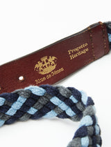 Close-up of the Pratese Belt - Blue by Blue de Gênes featuring blue and gray braided cotton webbing, a leather segment of full grain bull leather with a gold emblem, and Blue de Gênes and Progetto Heritage embossed on it, showcasing exquisite craftsmanship handmade in Italy.