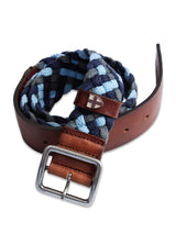 The Pratese Belt - Blue from Blue de Gênes features a coiled design with braided blue and black cotton webbing, brown full-grain bull leather accents, a silver rectangular buckle, and a small leather loop with an emblem. This handcrafted piece is made in Italy.